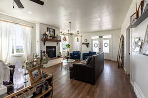 Living room featuring a fireplace, french doors, ceiling fan with notable chandelier, and dark hardwood / wood-style floors