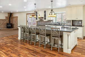 Kitchen with decorative backsplash, a center island, a wood stove, and dark wood-type flooring