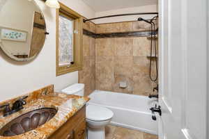 Full bathroom with tile patterned flooring, vanity, toilet, and tiled shower / bath