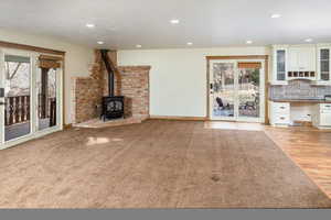 Unfurnished living room featuring a wood stove, a textured ceiling, and light wood-type flooring