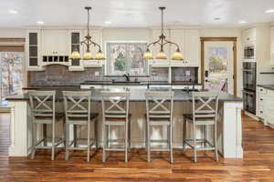 Kitchen with a large island with sink, backsplash, a kitchen breakfast bar, and sink