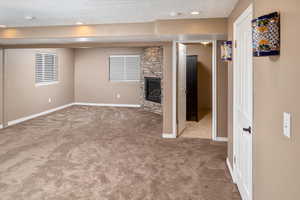 Living room featuring a textured ceiling, a stone fireplace, and light carpet