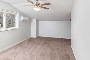 Bonus room with lofted ceiling, carpet, a wall mounted air conditioner, and ceiling fan