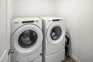 Clothes washing area featuring washing machine and dryer and hardwood / wood-style floors