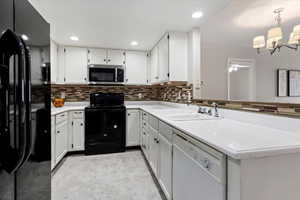 Kitchen with a chandelier, white cabinetry, and black appliances