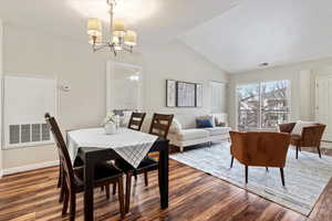 Dining space featuring a chandelier, wood-type flooring, and vaulted ceiling