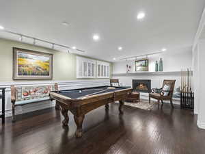 Playroom featuring a brick fireplace, dark hardwood / wood-style floors, crown molding, track lighting, and pool table