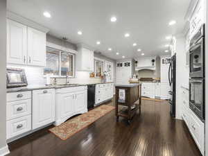 Kitchen with sink, hanging light fixtures, a kitchen island, dark hardwood / wood-style flooring, and white cabinets