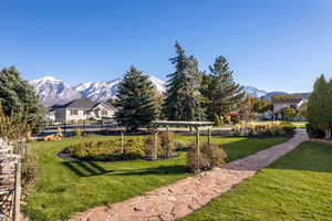 View of property's community with a mountain view, a pergola, and a lawn