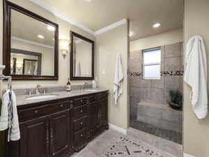 Bathroom featuring a tile shower, vanity, tile patterned floors, and ornamental molding