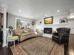 Living room with a fireplace, dark hardwood / wood-style flooring, and ornamental molding