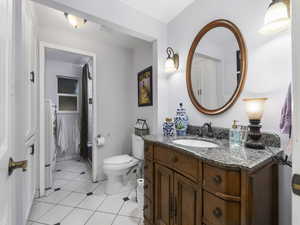 Bathroom with washing machine and clothes dryer, tile patterned floors, vanity, and toilet