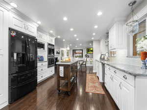 Kitchen featuring decorative backsplash, appliances with stainless steel finishes, light stone counters, white cabinets, and dark hardwood / wood-style floors