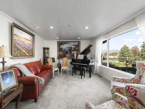 Carpeted living room featuring a textured ceiling and ornamental molding