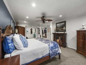 Carpeted bedroom featuring a spacious closet, ceiling fan, ornamental molding, and a closet