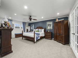 Bedroom with light carpet, ceiling fan, and ornamental molding