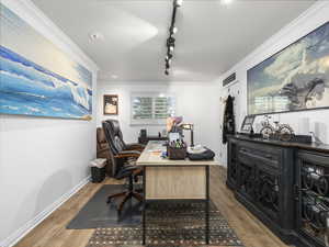 Office space featuring hardwood / wood-style flooring, track lighting, and ornamental molding