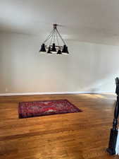 Unfurnished dining area with hardwood / wood-style floors and an inviting chandelier