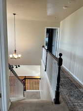 Stairs featuring carpet and an inviting chandelier