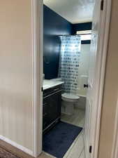 Full bathroom with vanity, shower / bath combination with curtain, and toilet