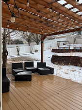 Snow covered deck featuring a pergola