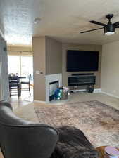 Living room with carpet, a textured ceiling, and ceiling fan