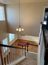 Staircase featuring hardwood / wood-style floors and a chandelier