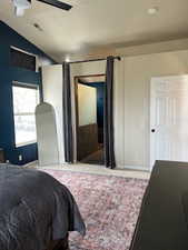 Carpeted bedroom featuring vaulted ceiling and ceiling fan