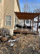 View of snow covered exterior featuring a pergola and a wooden deck