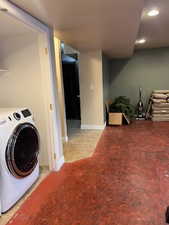 Washroom with light tile patterned flooring and washer / dryer