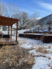 Yard covered in snow with a pergola and a deck with mountain view