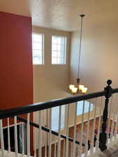 Stairway with a textured ceiling and a chandelier