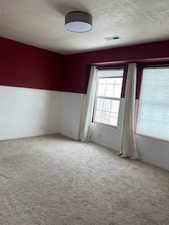 Empty room with a textured ceiling and light colored carpet