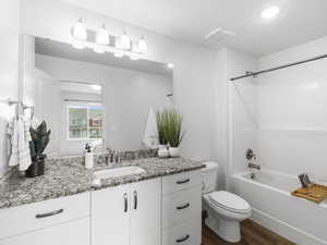 Full bathroom featuring shower / bathing tub combination, vanity, hardwood / wood-style flooring, and toilet