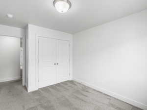 Unfurnished bedroom with a closet and light colored carpet