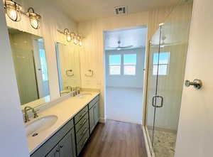 Bathroom featuring walk in shower, hardwood / wood-style floors, vanity, and ceiling fan