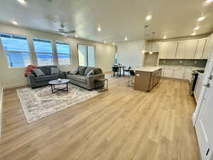 Living room with ceiling fan, sink, and light wood-type flooring