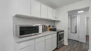 Kitchen with white cabinets, decorative backsplash, some stainless steel appliances