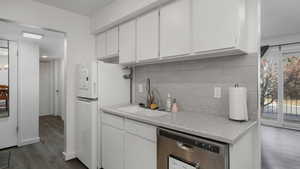 Kitchen featuring dishwasher, backsplash, white fridge, and white cabinets, stainless steel dishwasher