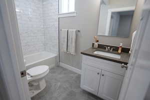 Full bathroom featuring vanity, toilet, and tiled shower / bath combo