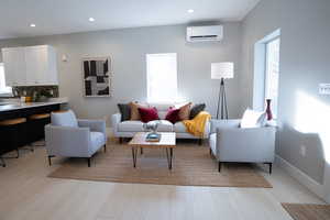 Living room with light wood-type flooring, sink, and a wall mounted AC