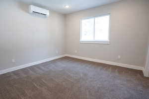 Spare room with carpet floors and an AC wall unit