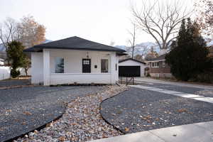 View of front of property featuring an outbuilding, a mountain view, a garage, and a porch