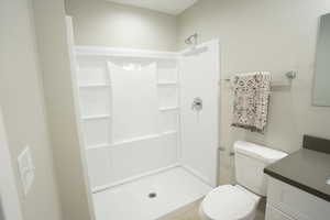 Bathroom featuring tile patterned floors, vanity, toilet, and walk in shower