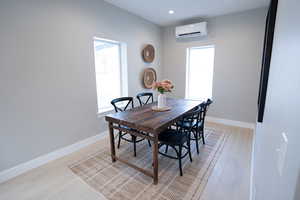 Dining space with a wall mounted AC and light wood-type flooring