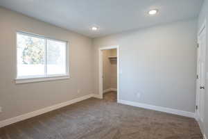 Unfurnished bedroom with carpet flooring, a textured ceiling, a spacious closet, and a closet