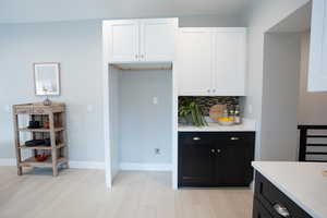 Kitchen featuring backsplash, light hardwood / wood-style flooring, and white cabinets