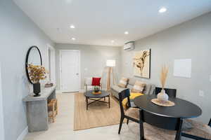 Dining space with light hardwood / wood-style floors and a wall unit AC