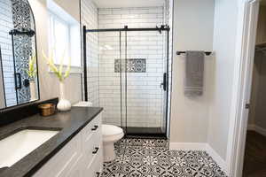 Bathroom featuring tile patterned flooring, vanity, toilet, and an enclosed shower