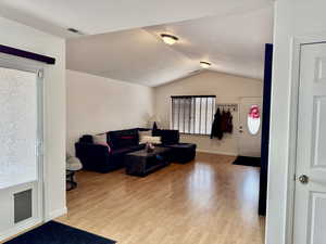 Living room with light hardwood / wood-style flooring, a textured ceiling, and vaulted ceiling